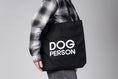 Bild in Galerie-Betrachter laden, Schwarzer Jutebeutel mit weißem „Dog Person“-Print von Karma Hund, frontal fotografiert.