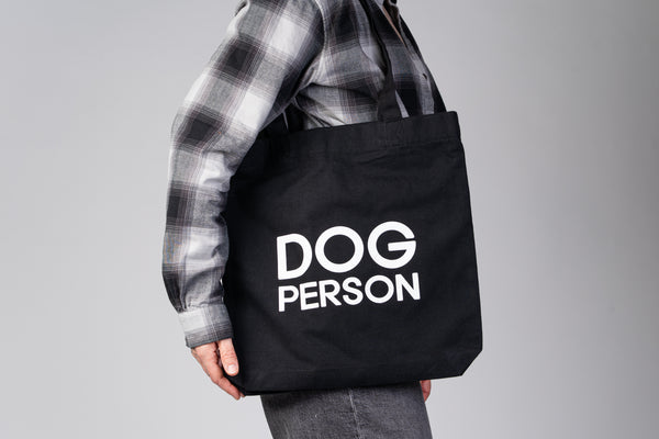 Schwarzer Jutebeutel mit weißem „Dog Person“-Print von Karma Hund, frontal fotografiert.